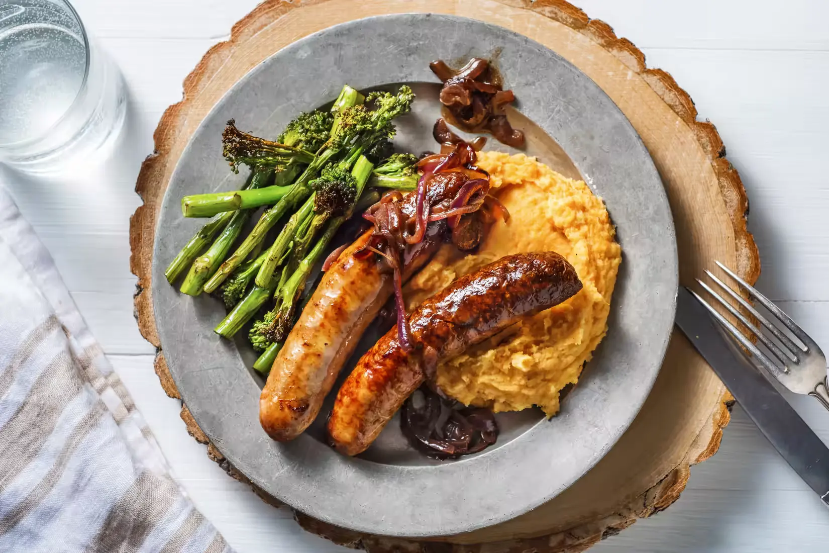 https://www.thebookofdishes.com/wp-content/uploads/2023/07/Honey-Mustard-Sausages-and-Sticky-Red-Onion-Gravy-with-Sweet-Potato-Mash-and-Tenderstem-Broccoli.webp